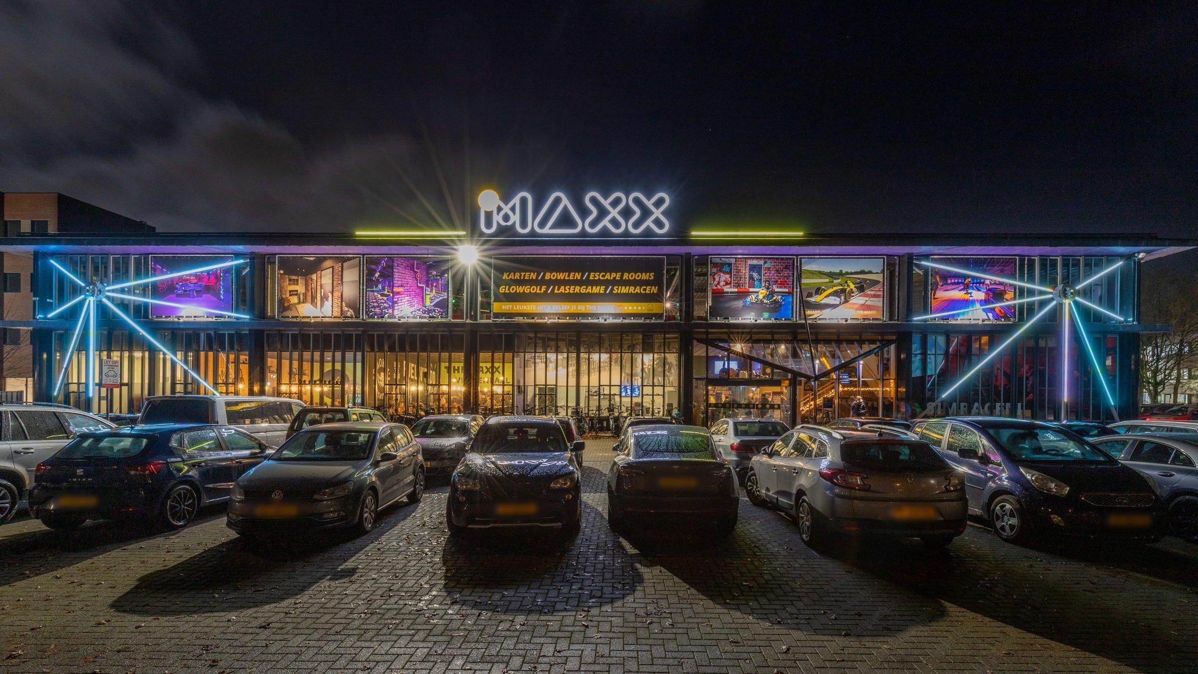 Verlichte gevel van The Maxx in de avond
