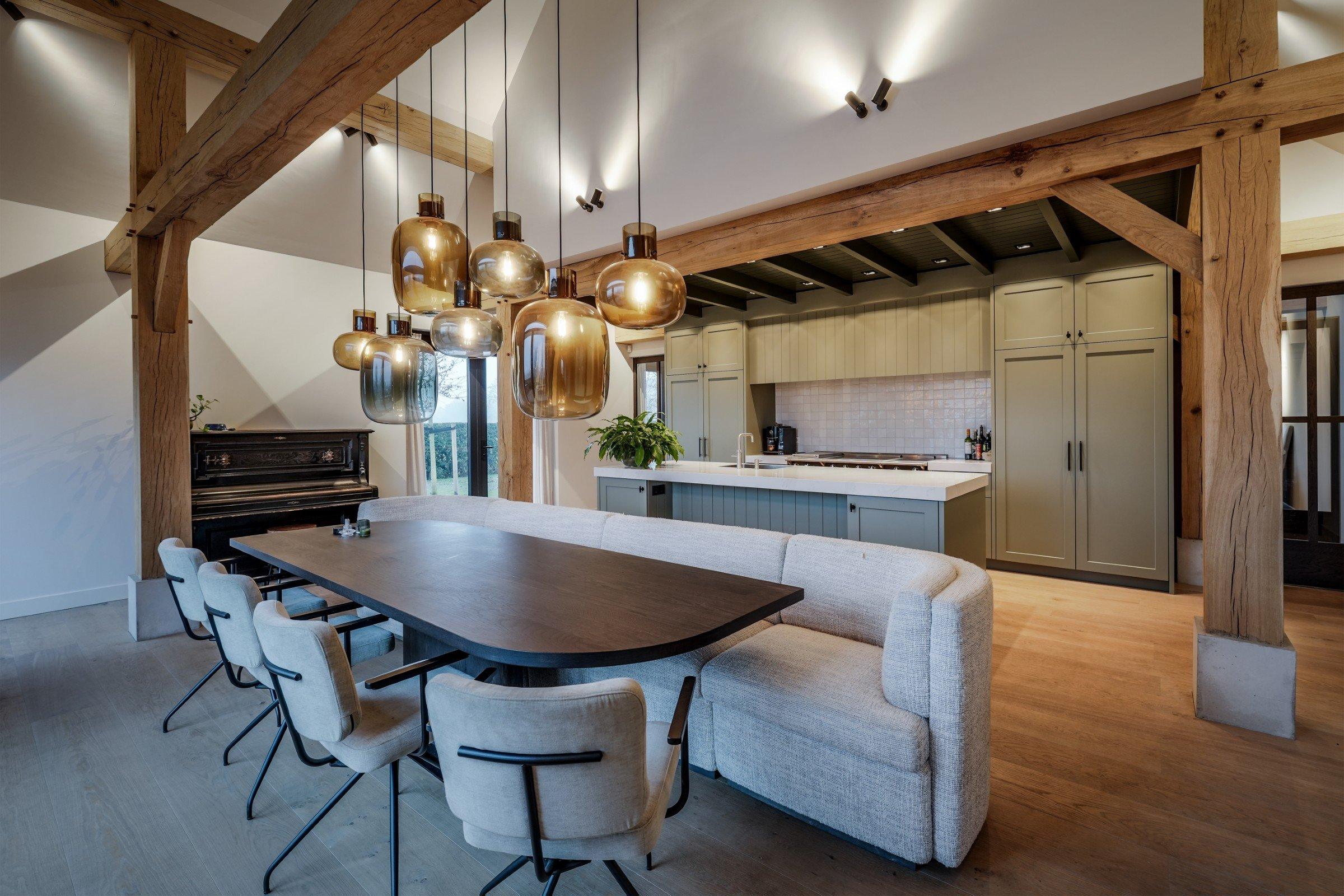 Eettafel onder glazen hanglampen tussen eiken spanten