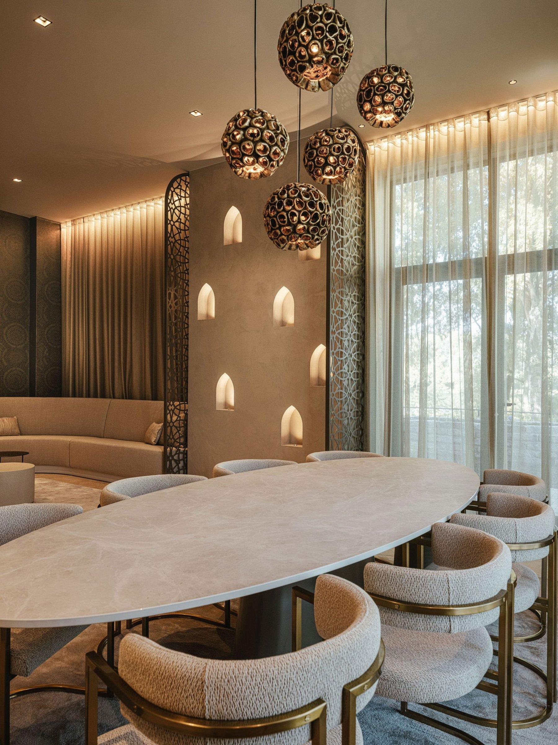 Ovale tafel onder hanglampen voor hoge ramen