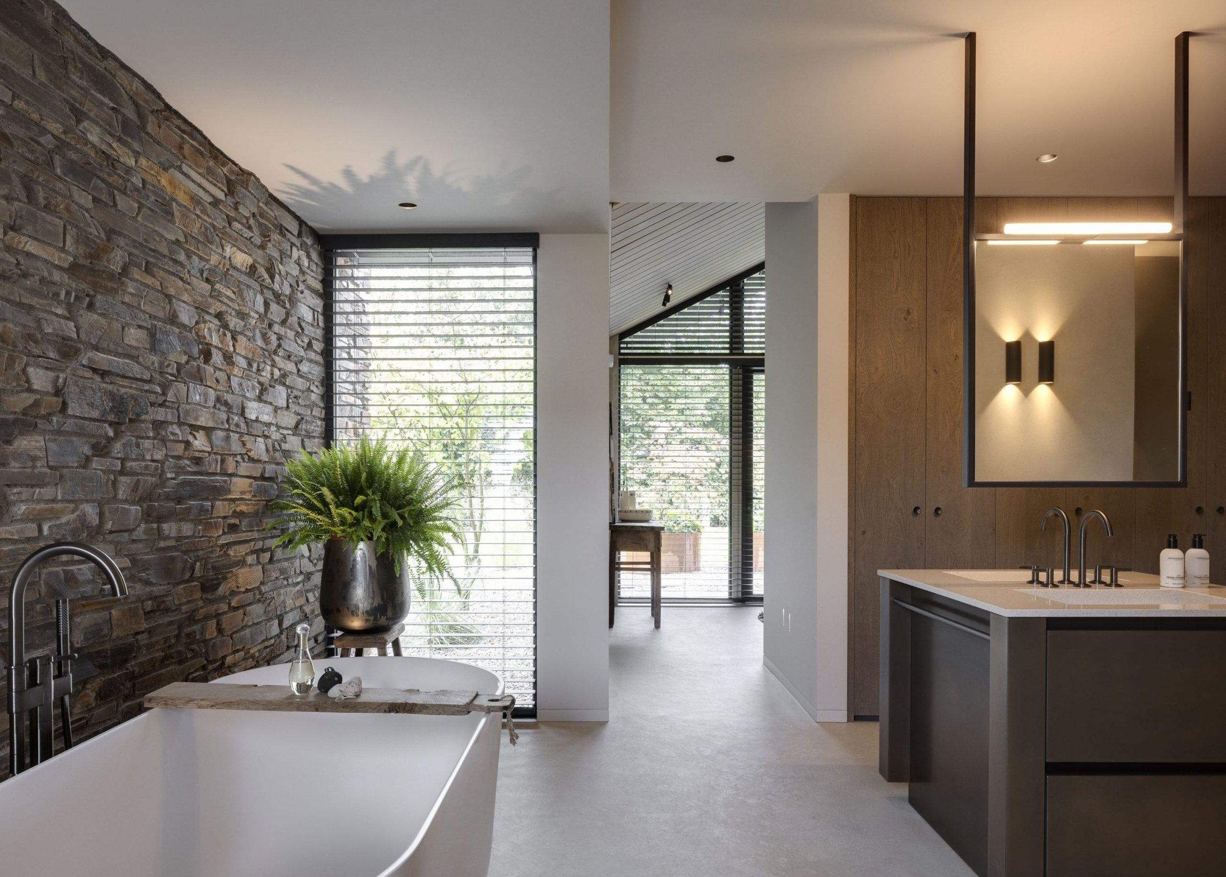 Badkamer met natuursteen wand en spiegel met verlichting