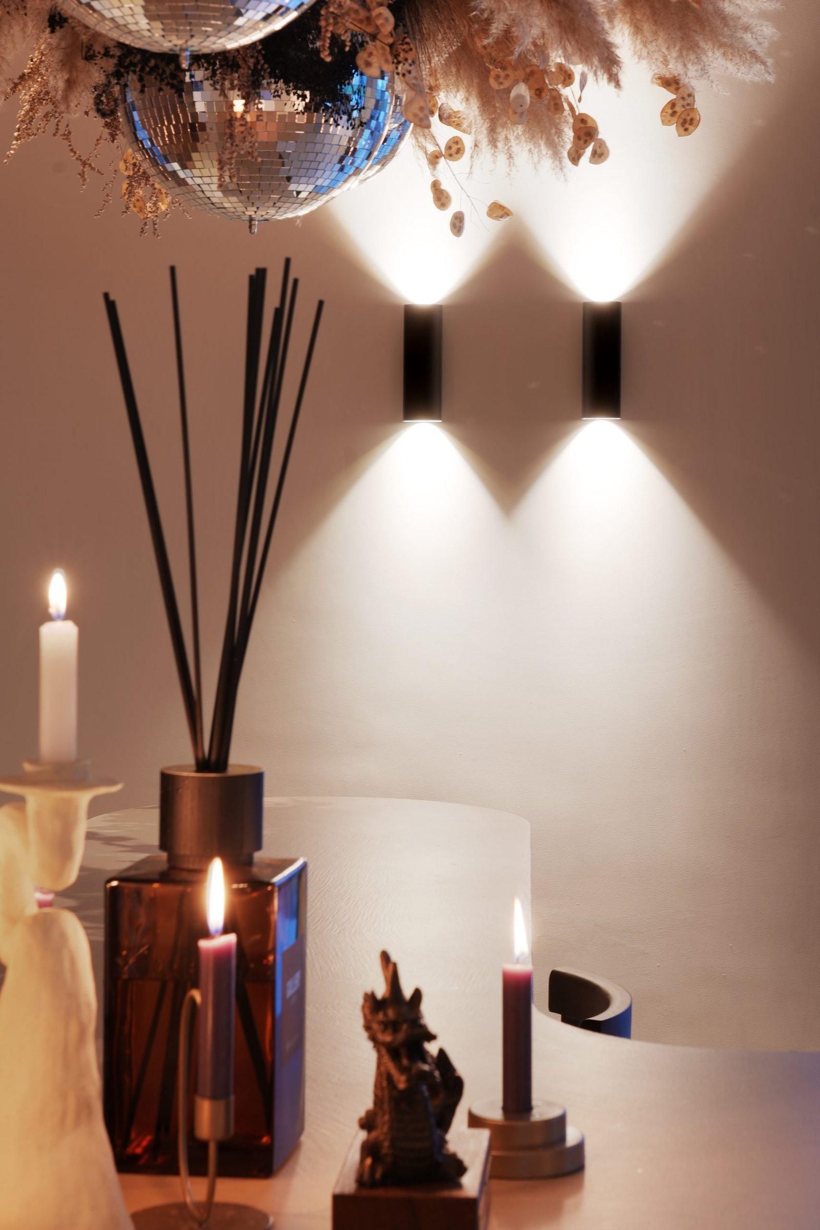 Wandlamp boven een dressoir met kaarsen